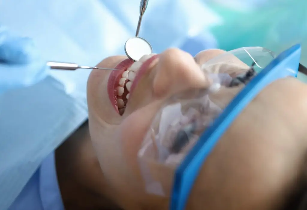 Dentist examining oral cavity of woman patient in clinic using tools closeup